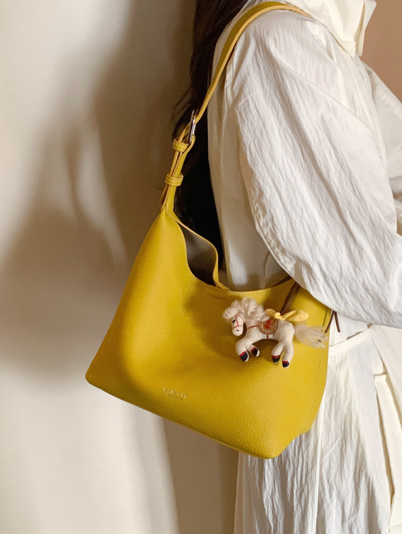 Yellow shoulder handbag worn over a white outfit