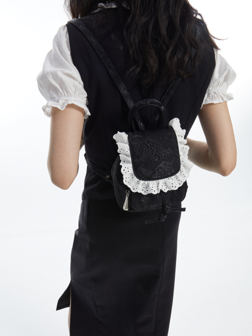 Black mini backpack with white lace trim worn on a model