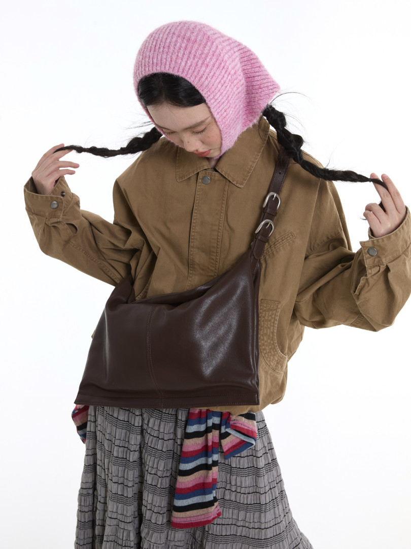 Model wearing a khaki jacket, pink knit hood, and brown crossbody bag