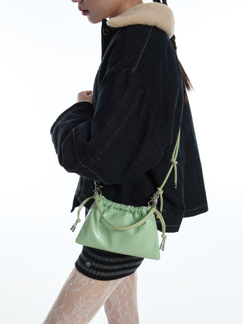 Mint green drawstring shoulder bag worn on a model with a black jacket