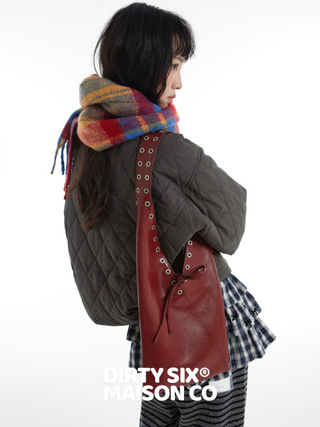 Model wearing a quilted jacket with a plaid scarf and red shoulder bag