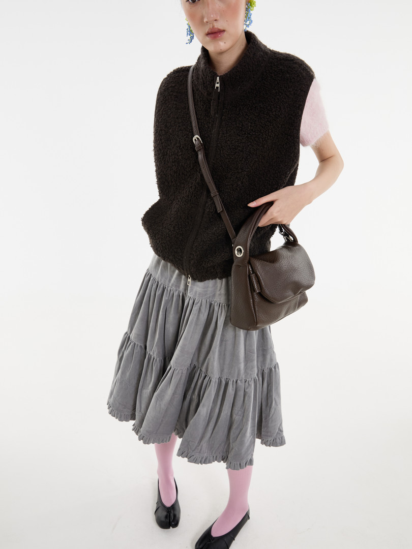 Model wearing a black sherpa zip vest with a brown crossbody bag