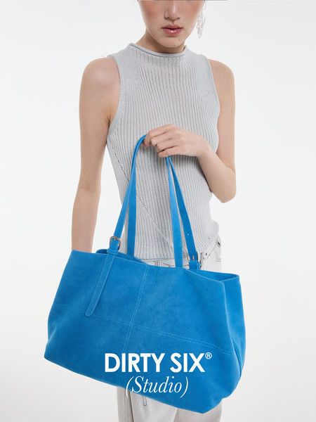 Model holding a large blue tote bag on a white background