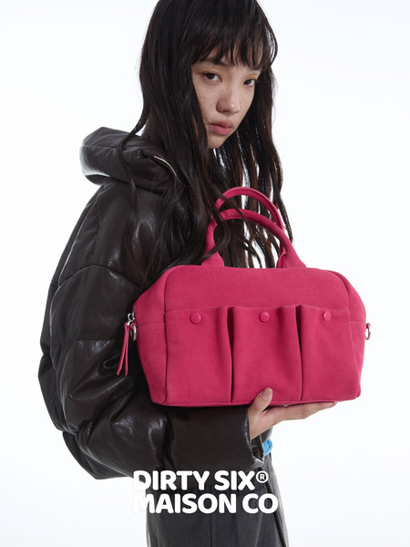 Model holding a bright pink handbag against a white background
