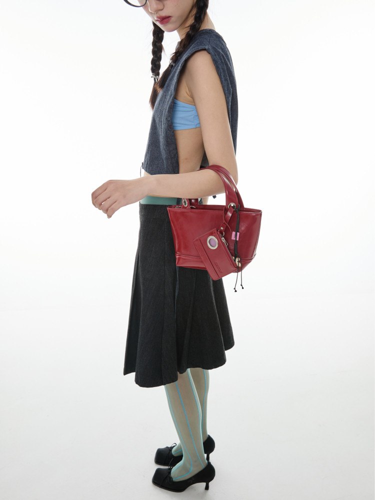 Model wearing a red leather handbag with a matching pouch