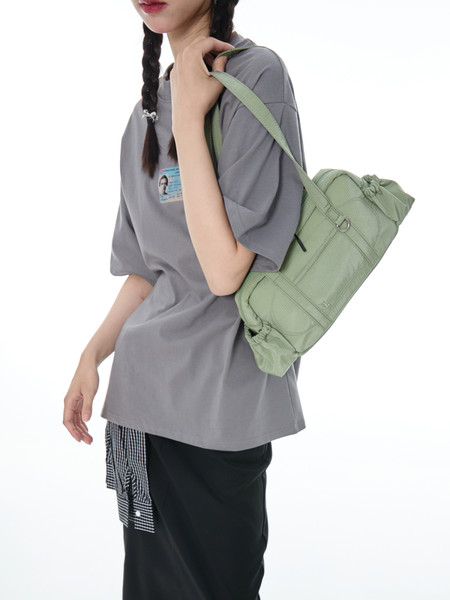 Model wearing a light green shoulder bag with a gray oversized T-shirt