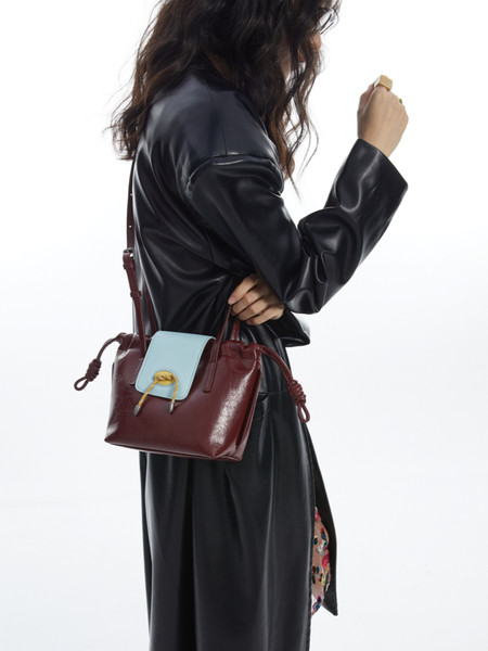 Burgundy leather handbag with light blue flap, worn on a model