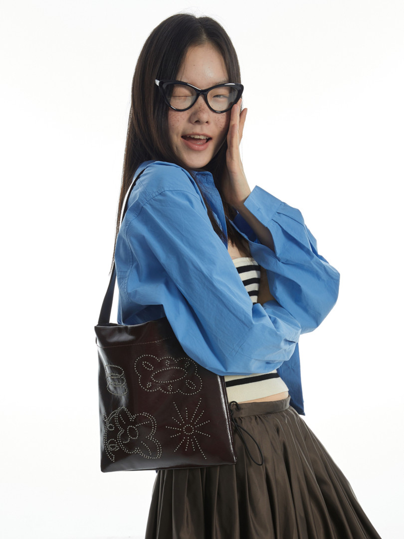 Model wearing a blue shirt and carrying a black tote bag