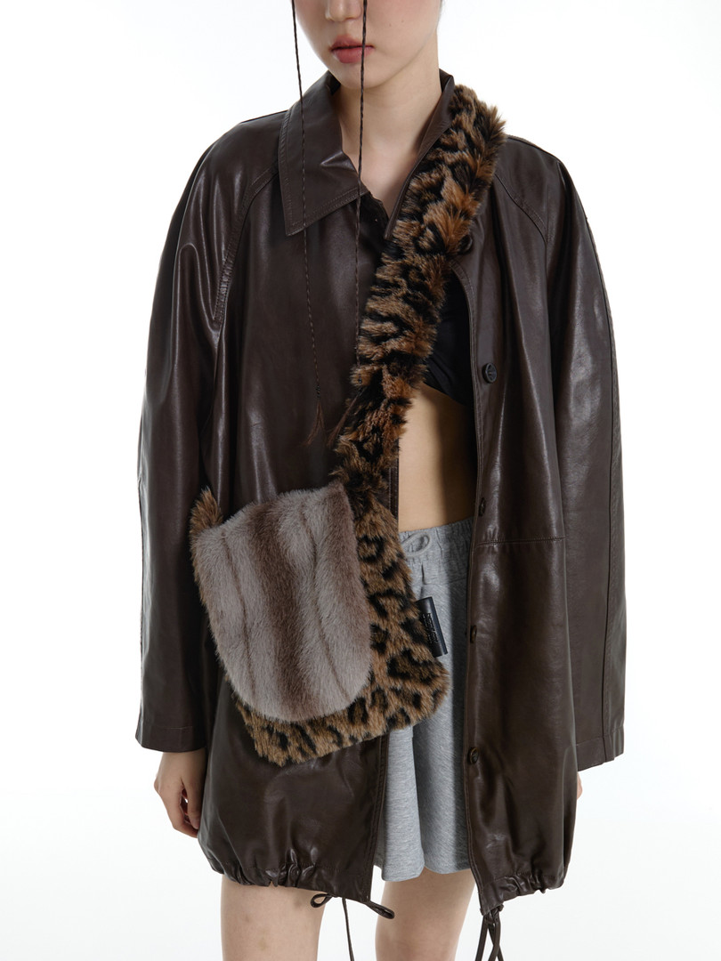 Model wearing a dark brown leather coat with a faux fur shoulder bag