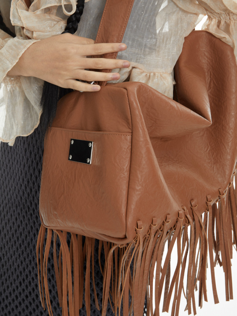 Brown leather fringe handbag worn by a model