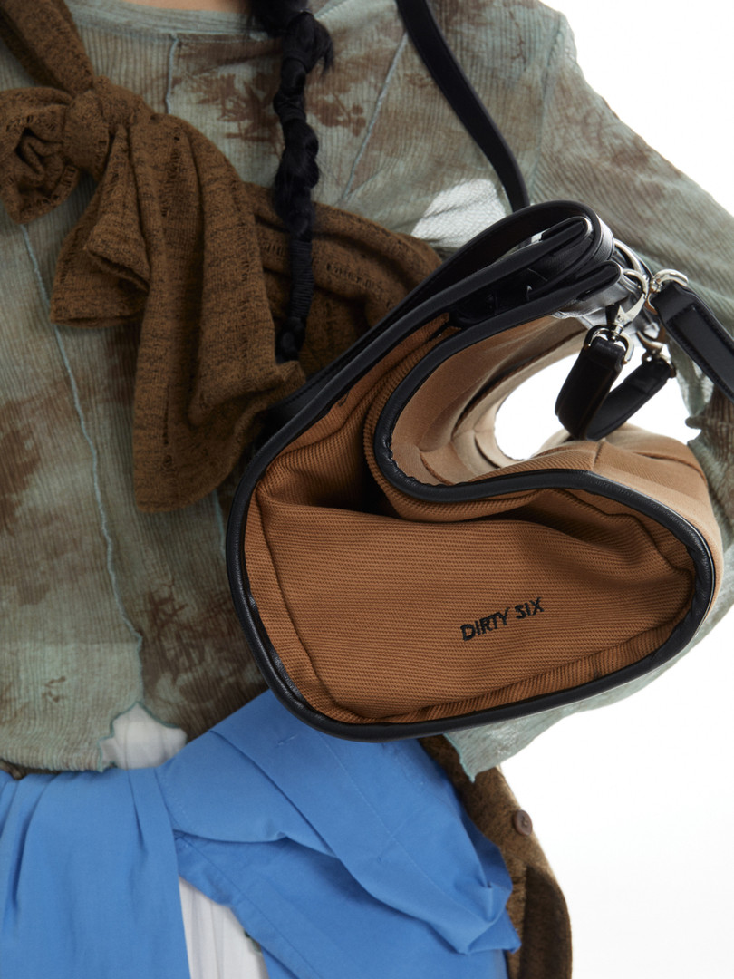 Brown and black crossbody bag shown in a fashion flat lay