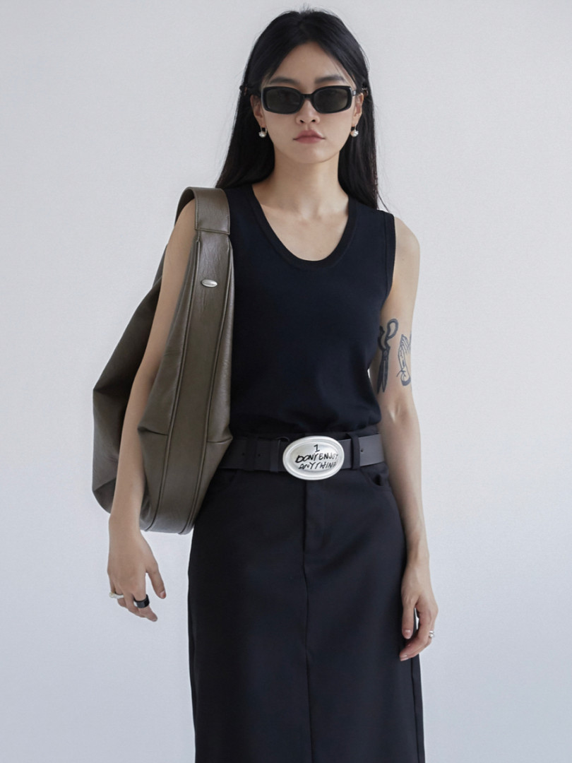 Model wearing a black sleeveless outfit with sunglasses and a brown shoulder bag