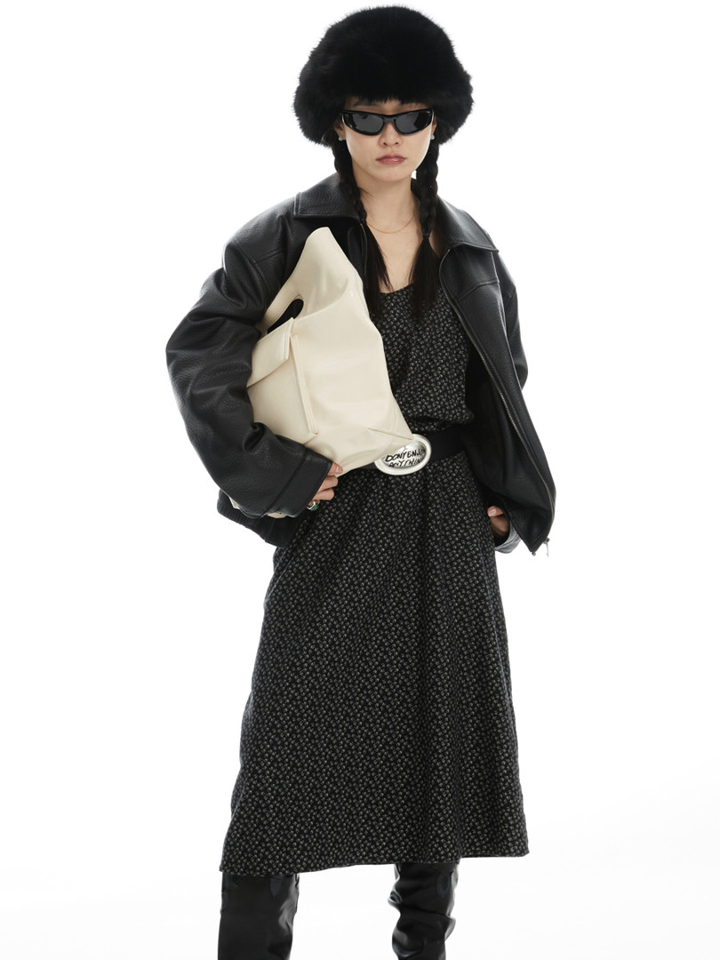Model wearing a black leather jacket, patterned dress, fur hat, and cream bag