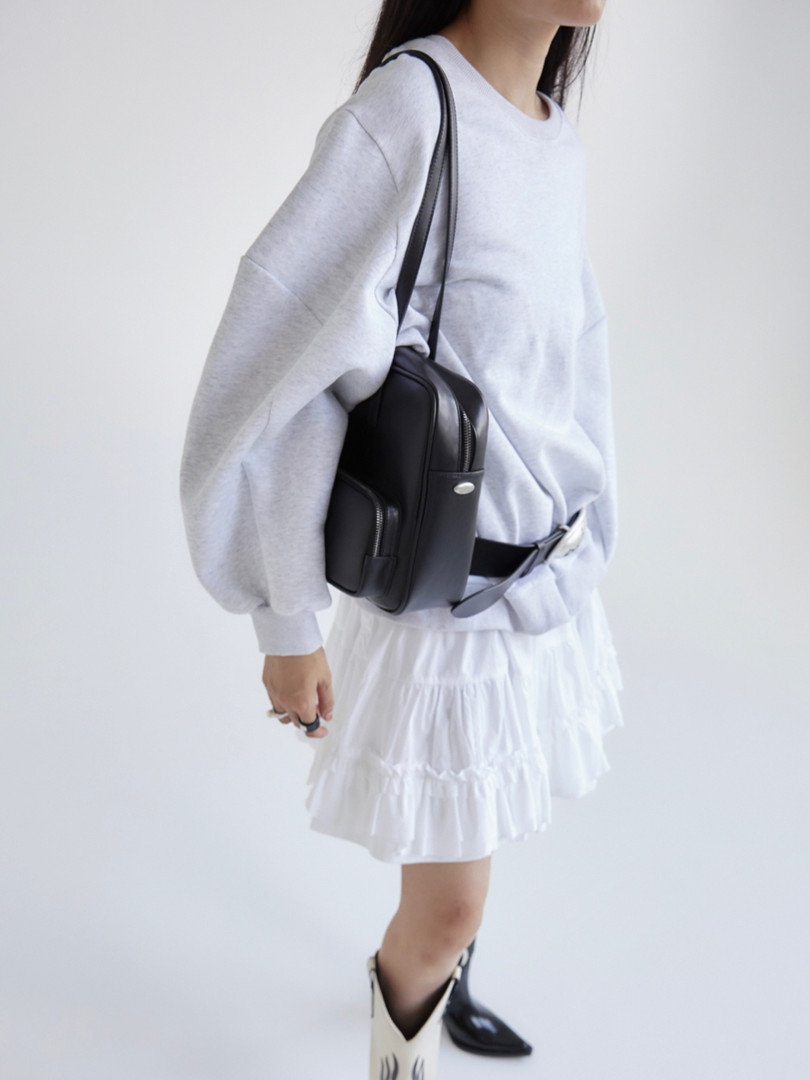 Black crossbody bag worn by a model with a casual outfit
