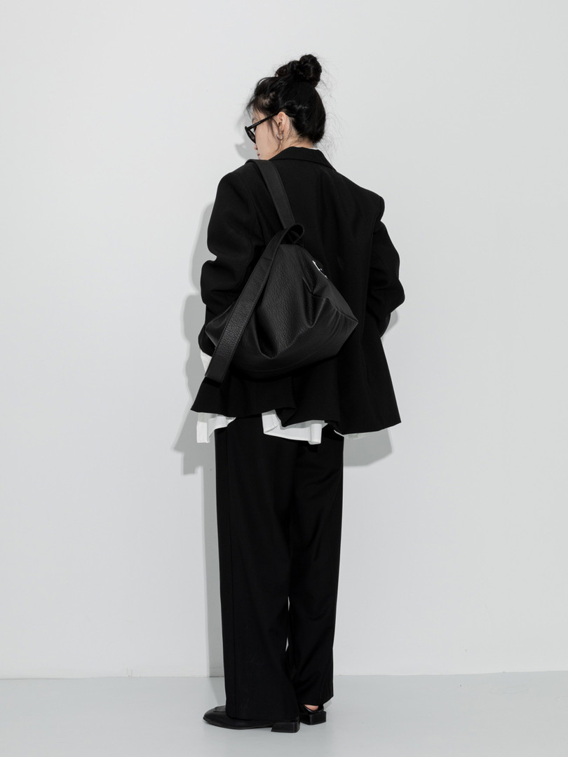 Model wearing an oversized black outfit with a large black shoulder bag