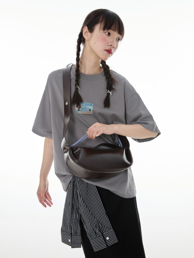 Model wearing a gray oversized T-shirt with a dark brown crossbody bag