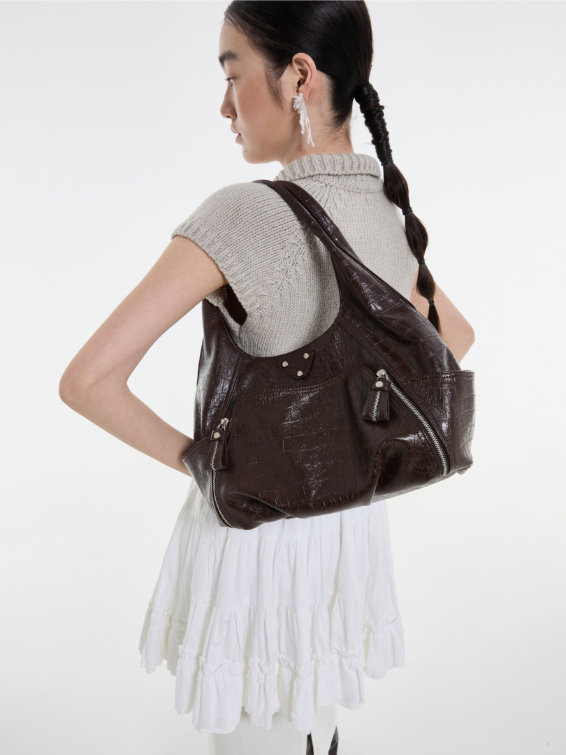 Brown leather shoulder bag worn by a model