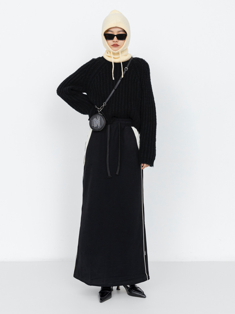 Model wearing a black long knit outfit with hood and sunglasses