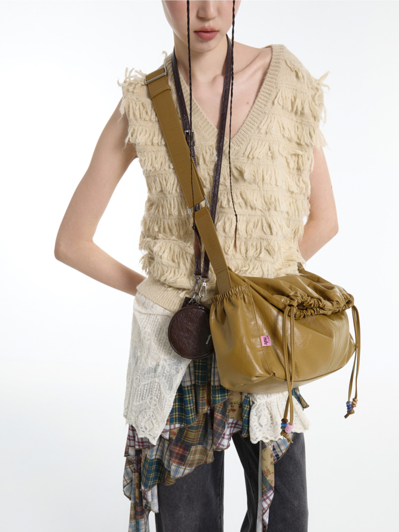 Model wearing a cream textured sleeveless top with layered skirt and a tan crossbody bag