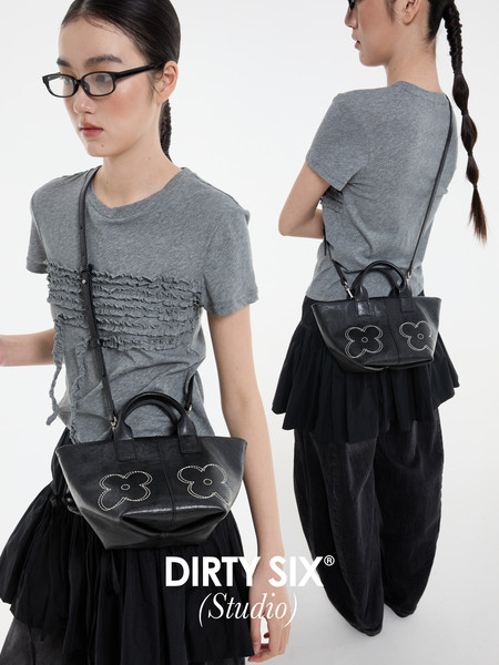 Model wearing a gray ruffled T-shirt with a black mini handbag