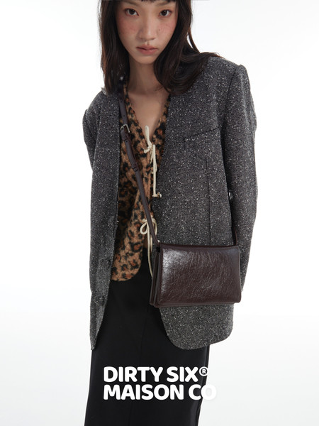 Model wearing a dark textured blazer with a brown crossbody bag