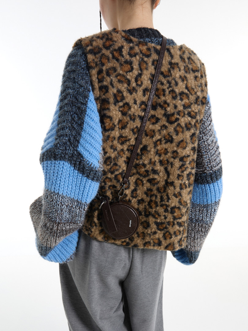 Model wearing a fuzzy leopard-print and striped knit sweater with a small crossbody bag