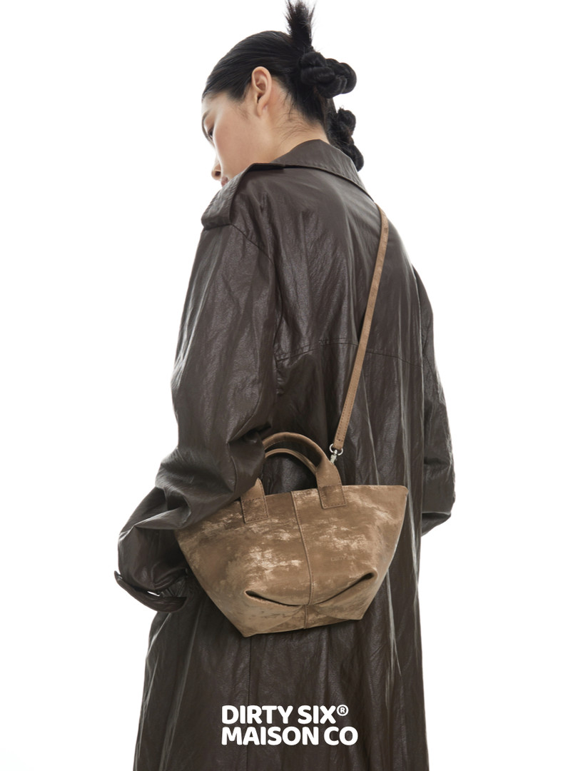 Model wearing a dark brown leather coat with a tan crossbody handbag