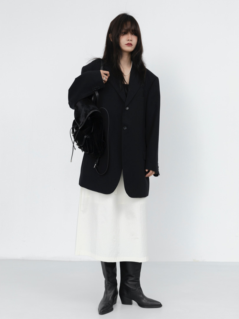 Model wearing a black oversized blazer with a white skirt and black boots