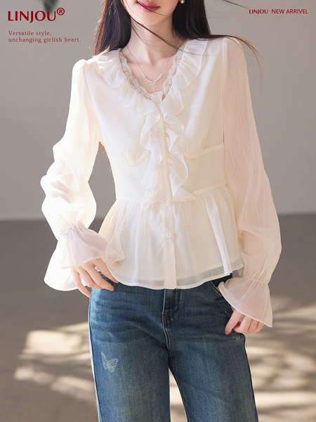 Woman wearing a sheer white ruffled blouse with long sleeves and buttons