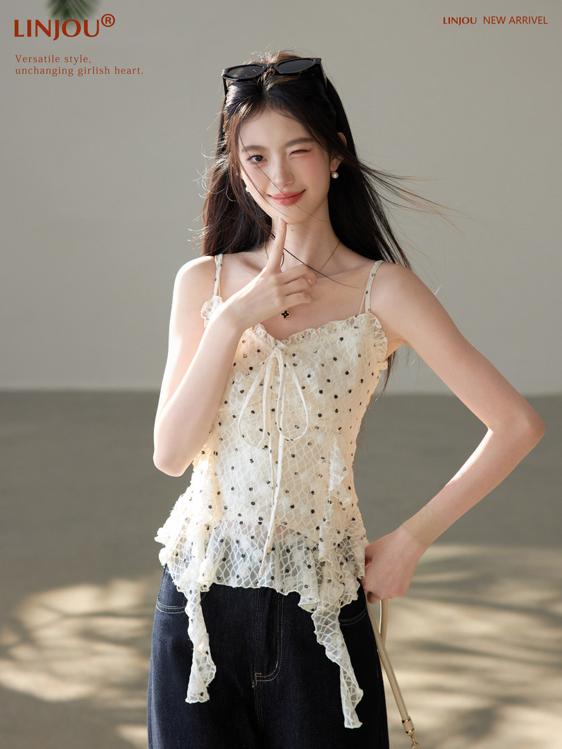 Woman wearing a white lace camisole top with ruffle details and dark jeans