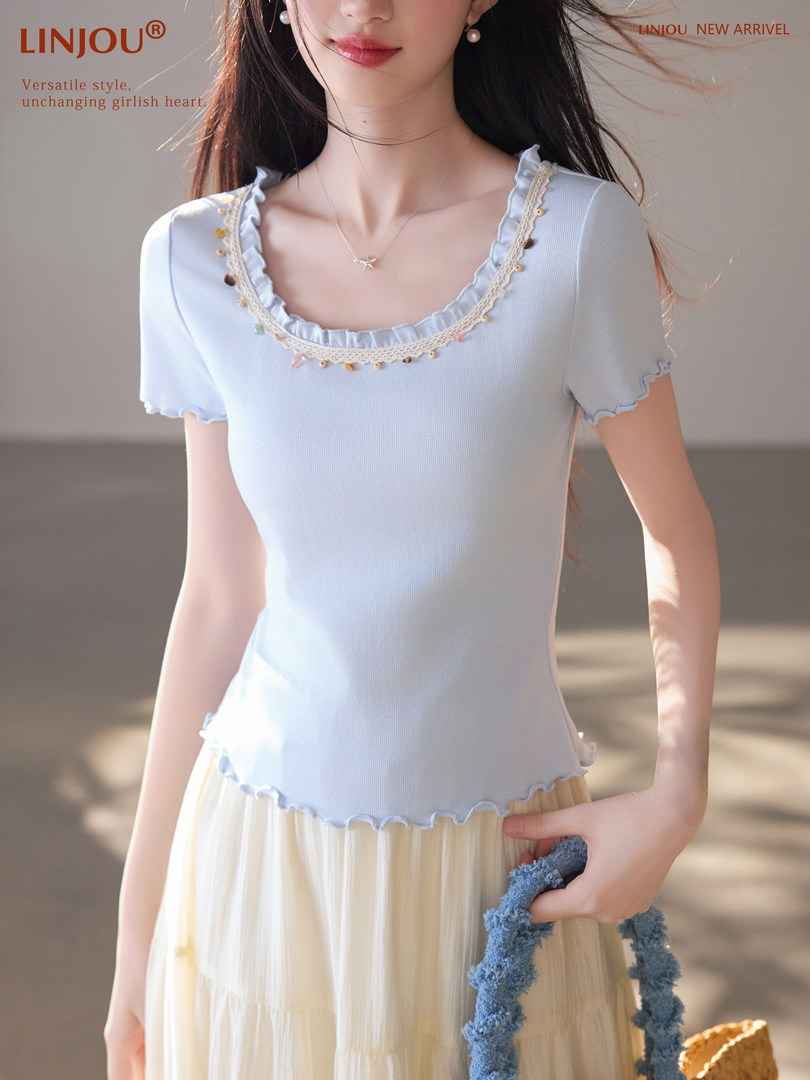 Model wearing a light blue ruffled short-sleeve top with a pastel skirt