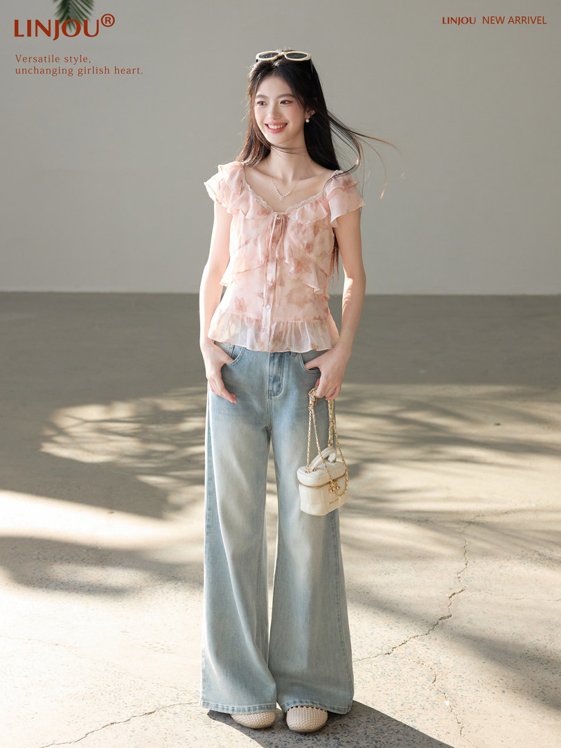 Model wearing a light pink ruffled blouse with wide-leg jeans and a small shoulder bag