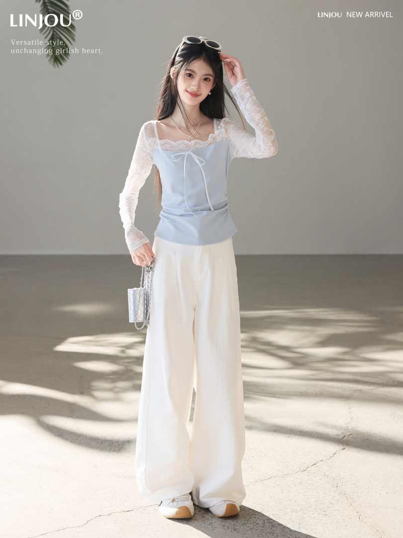 Woman wearing a light blue lace long-sleeve top with white wide-leg pants