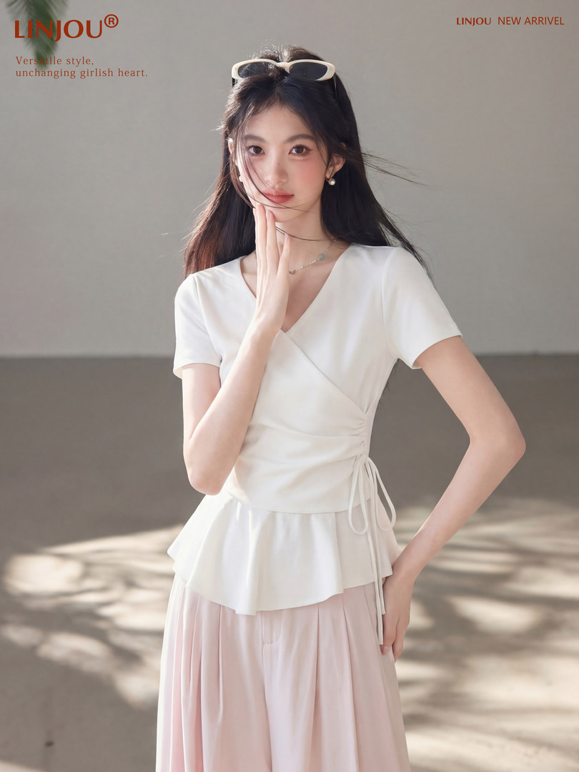 Woman wearing a white wrap-style short-sleeve dress with a pleated skirt