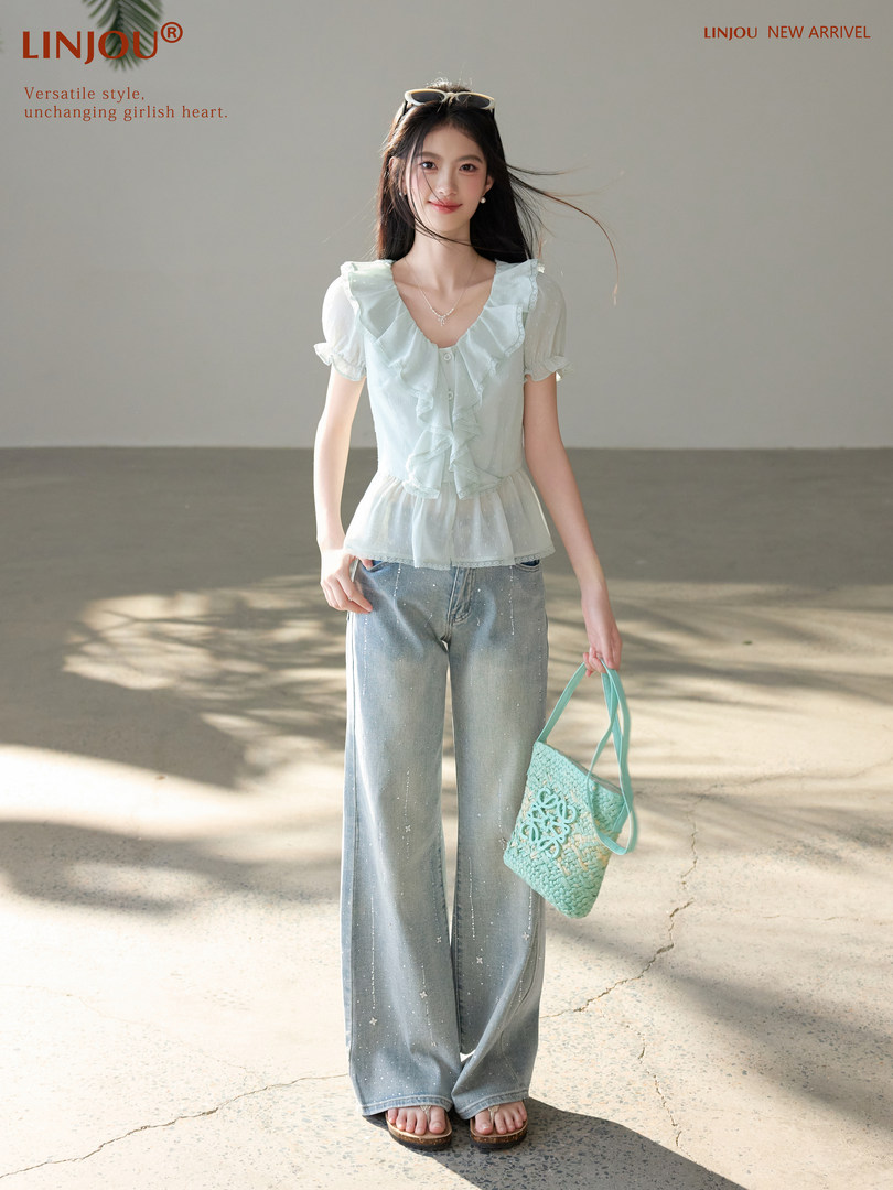 Model wearing a light ruffled blouse with wide-leg jeans and a woven tote bag