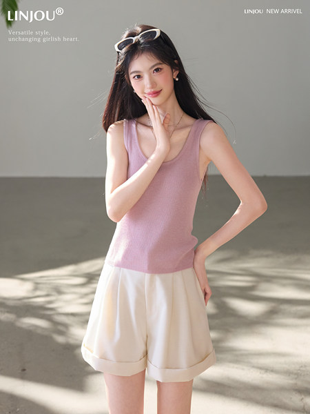 Model wearing a pink ribbed tank top with cream shorts