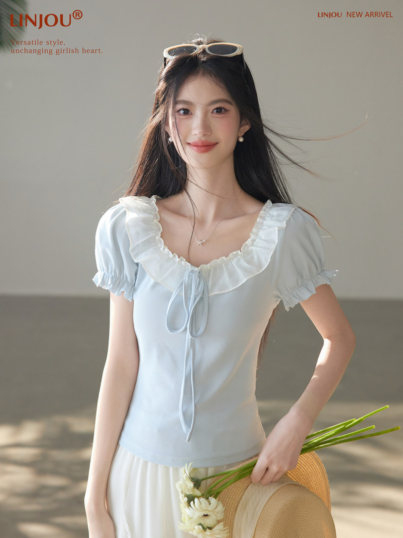 Woman wearing a light blue ruffled short-sleeve blouse with a tie front