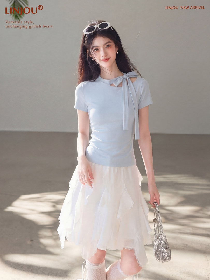 Model wearing a light blue short-sleeve top with bow detail and a white layered skirt