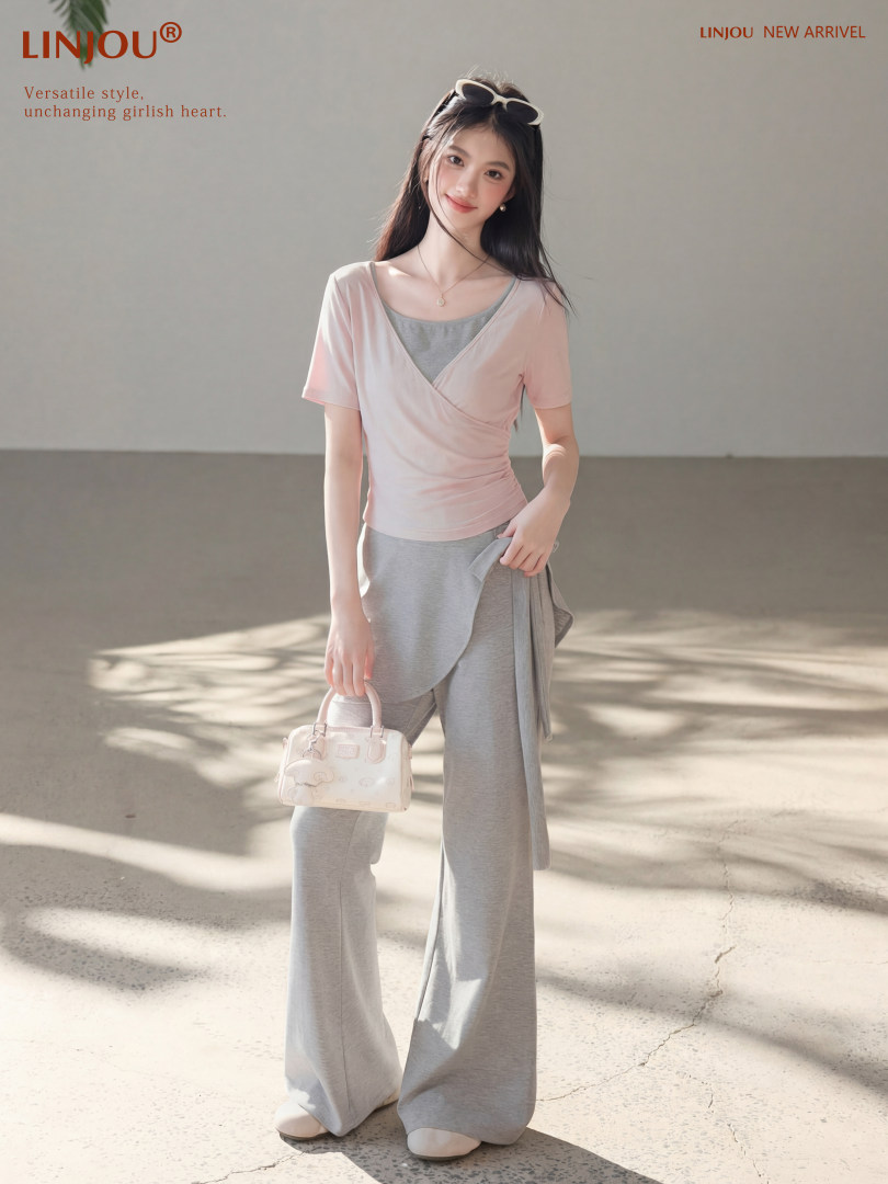Model wearing a pink wrap top and gray wide-leg lounge set with a small handbag