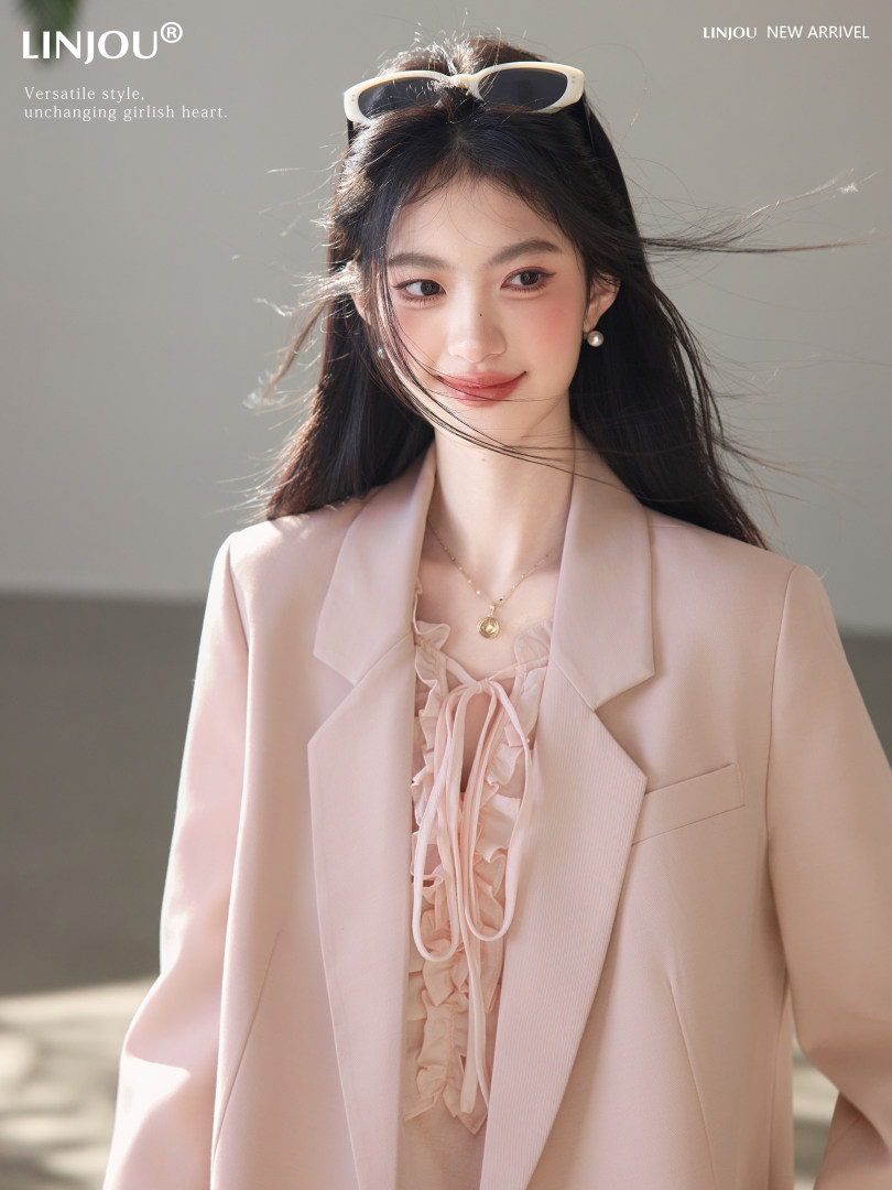 Woman wearing a pale pink blazer and ruffled blouse