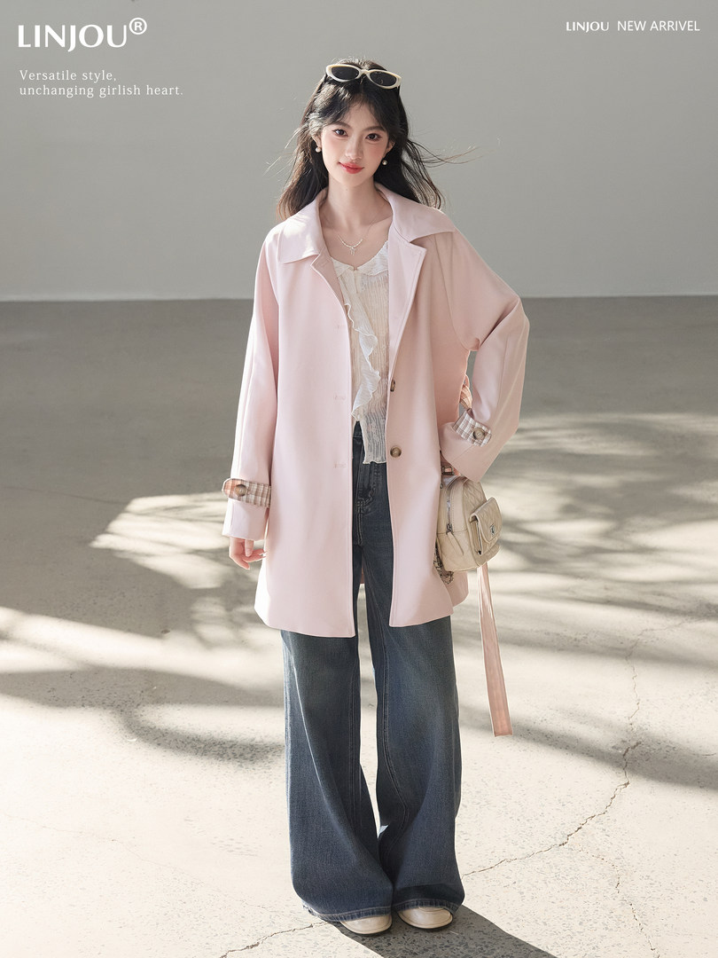 Model wearing a light pink oversized coat with jeans and a white blouse