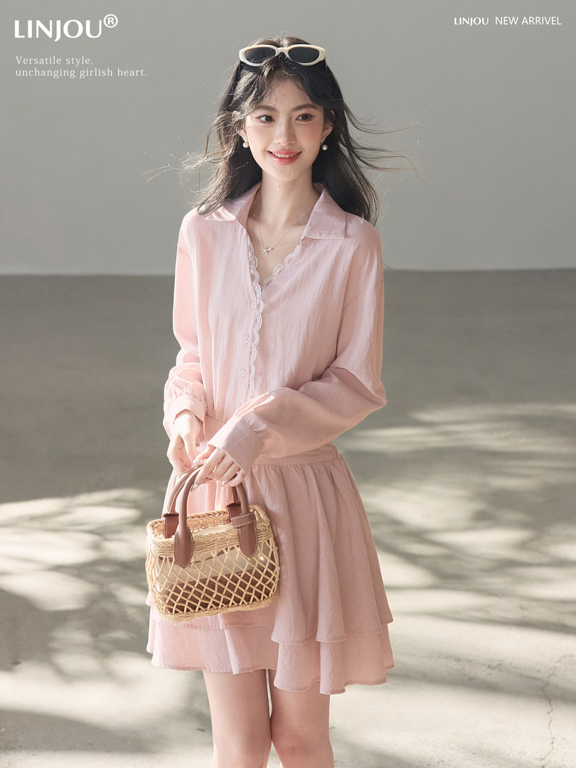 Model wearing a light pink flowing dress and holding a woven handbag