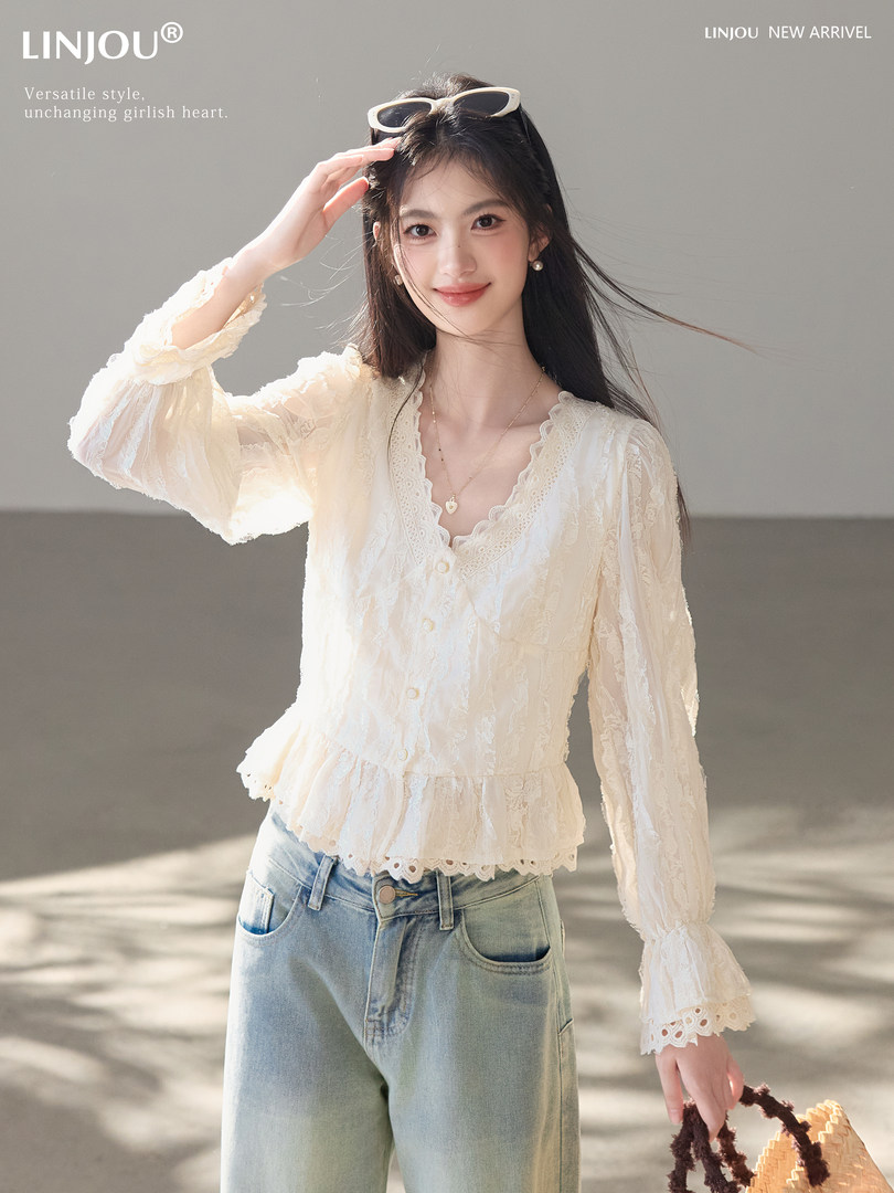 Model wearing a cream lace long-sleeve blouse with blue jeans