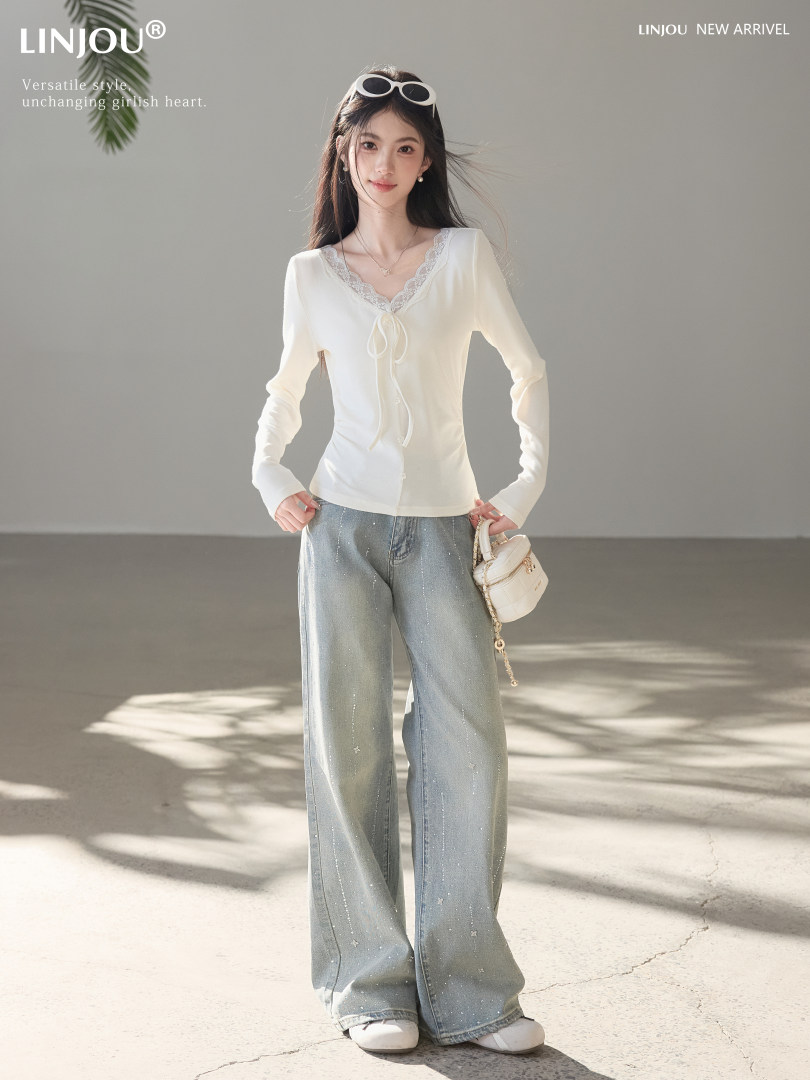 Model wearing a white lace-trim long-sleeve top with wide-leg light blue jeans and a small white handbag