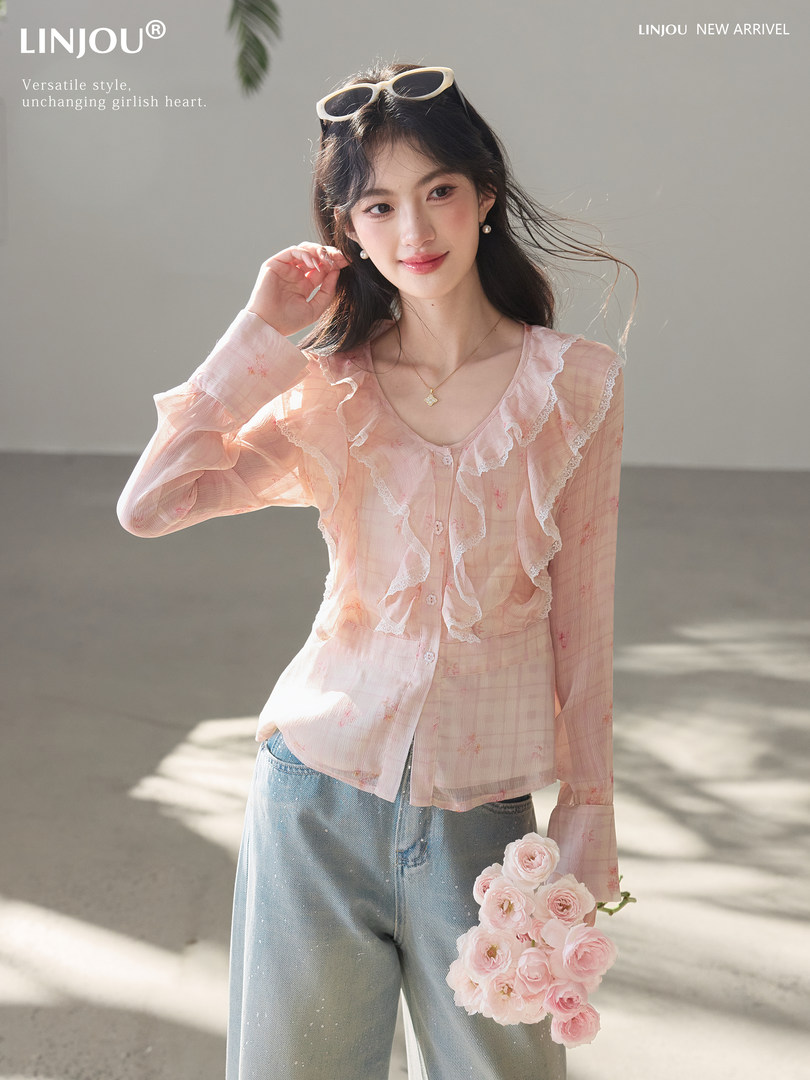Model wearing a sheer pink ruffled long-sleeve blouse with jeans