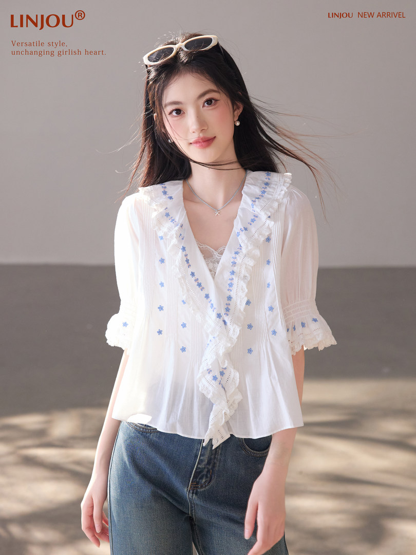 Woman wearing a white ruffled embroidered blouse with jeans