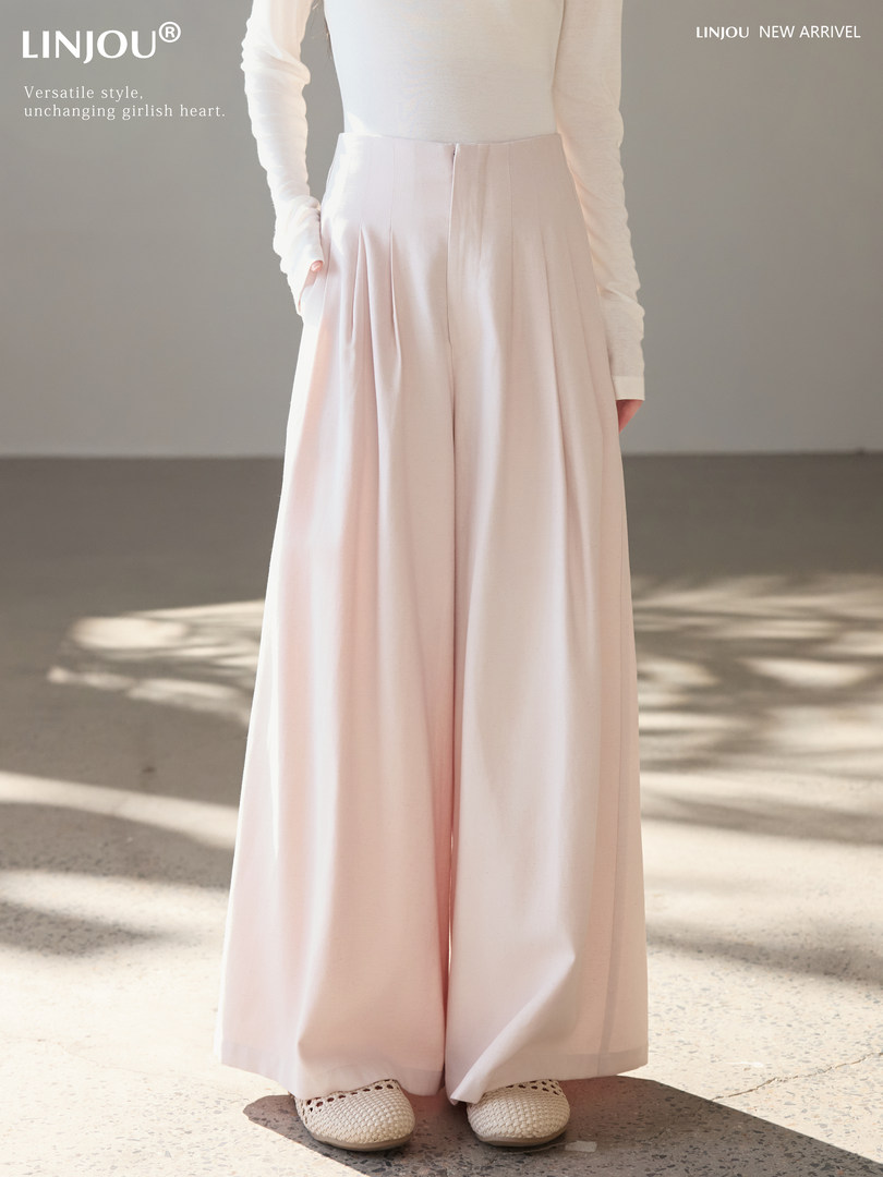 Model wearing light pink high-waisted wide-leg trousers