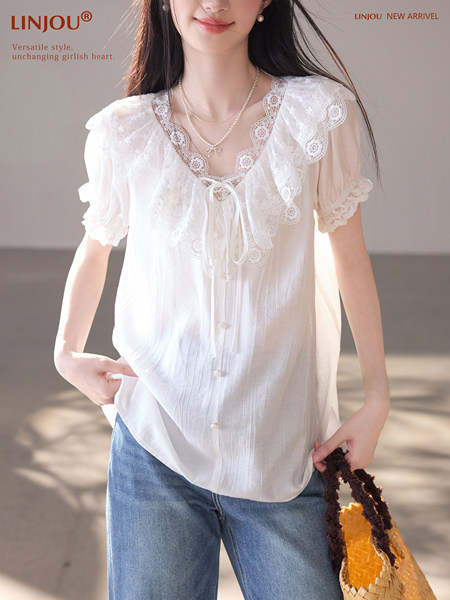 Model wearing a white lace short-sleeve blouse with a tie neckline