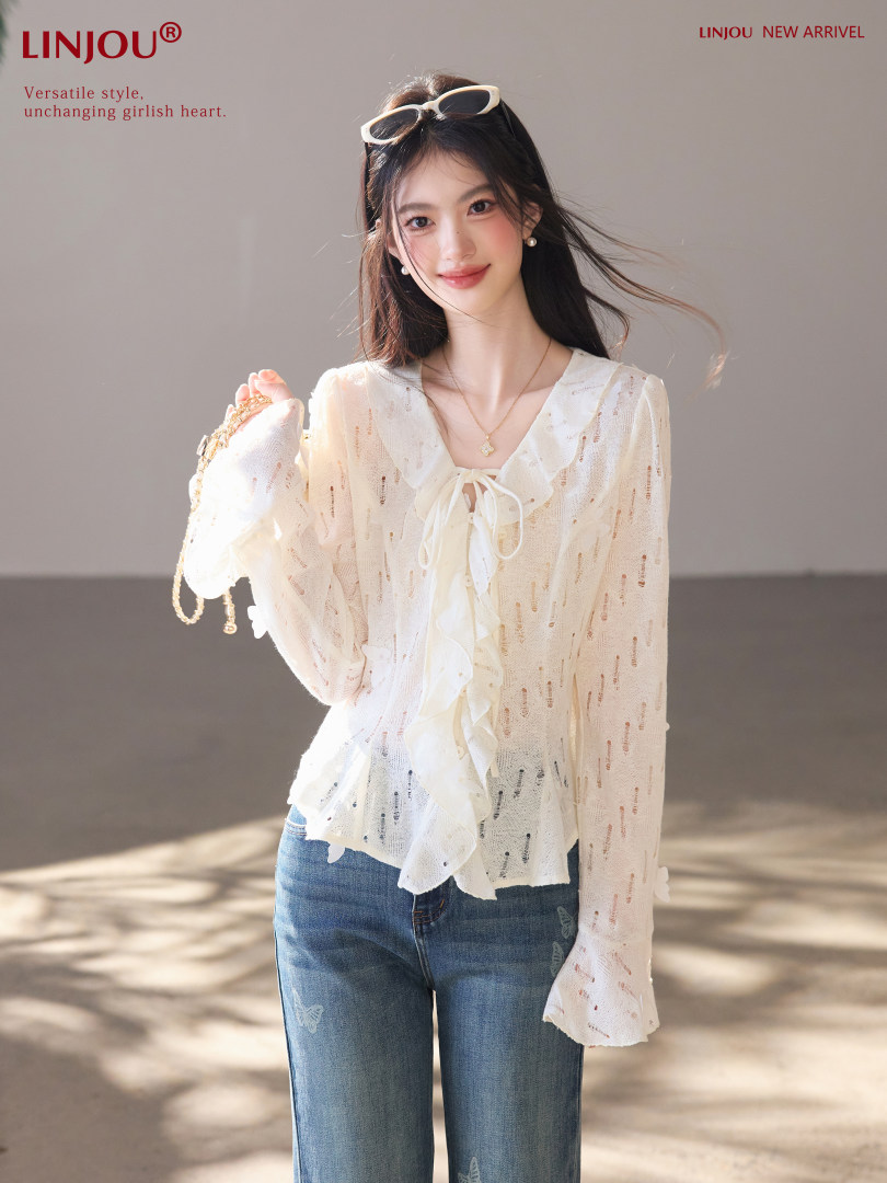 Model wearing a sheer white ruffled blouse with blue jeans