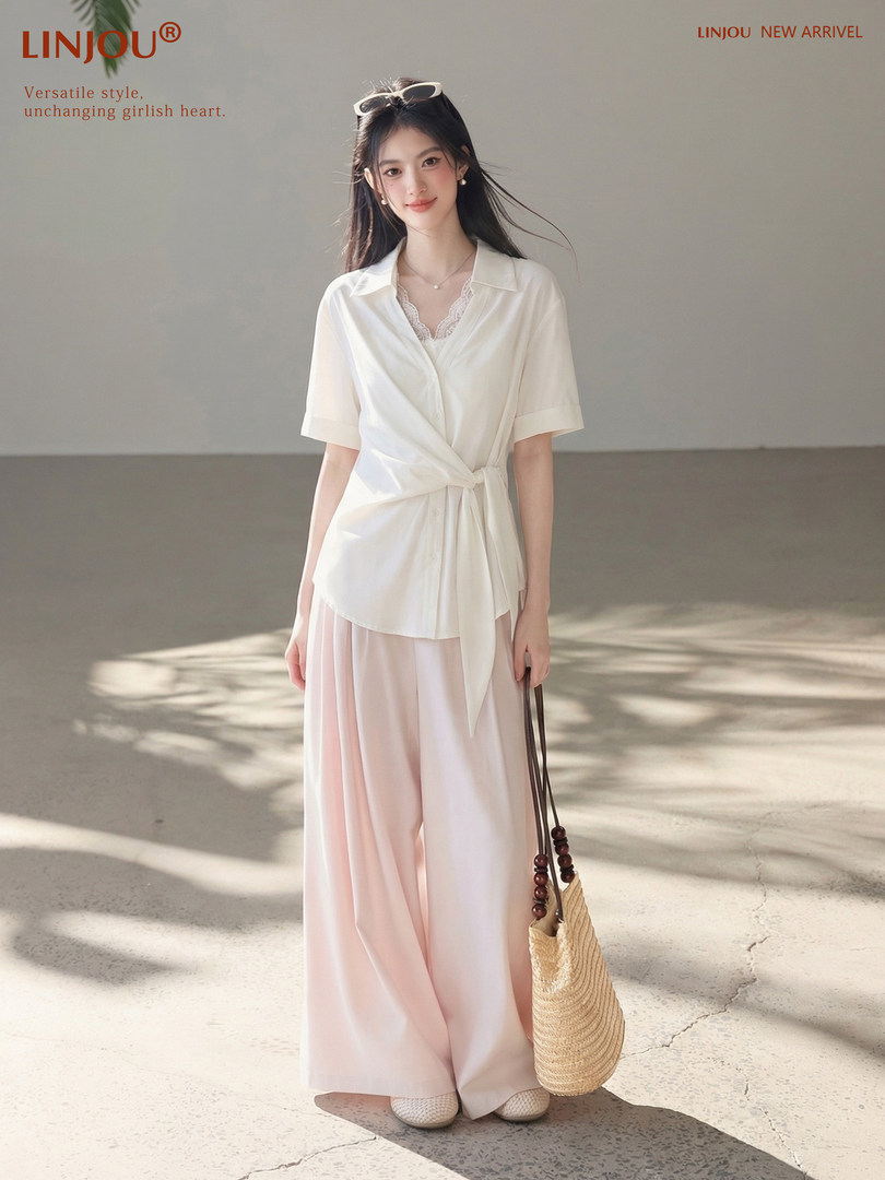 Woman wearing a white tie-front blouse and pink wide-leg pants with a straw bag